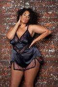 Woman wearing a black lace nightgown against a textured brick wall.
