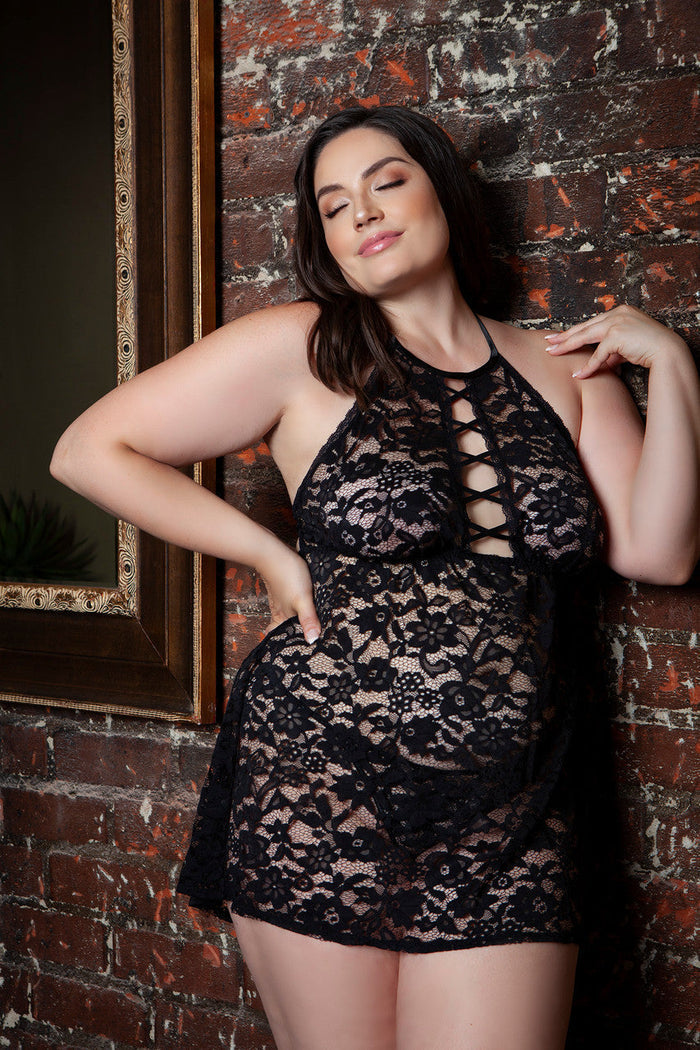Woman wearing a black lace nightgown against a brick wall.