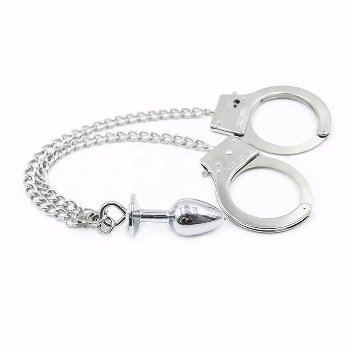 BDSM handcuffs with a chain that leads to a silver anal plug. Represents the BDSM community.